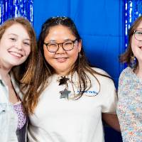 Three students pose in front of blue back drop